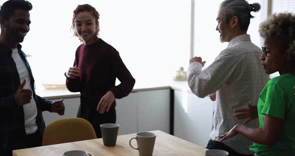 Multiracial happy friends having fun dancing at home kitchen