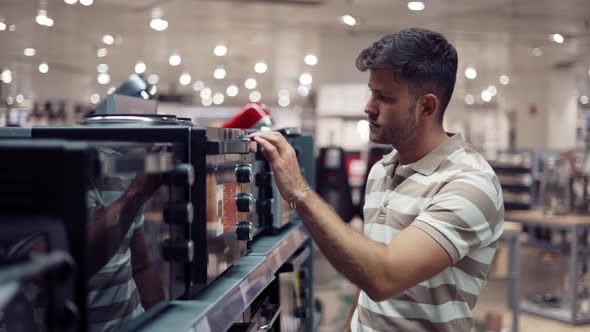 Man Choosing Microwave Oven in Shop