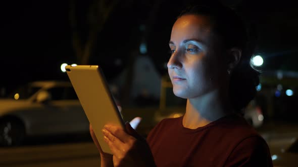 A Woman Uses a Tablet in a City Night. Technology, Communication and Navigation.