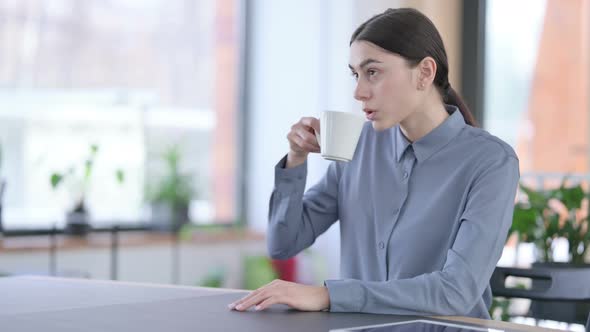 Attractive Young Latin Woman Drinking Coffee in Office