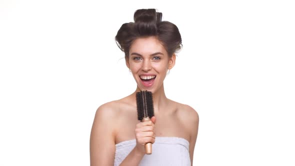 Caucasian Topless Lady with Hair Curlers Having Fun Over White Background in Slowmotion