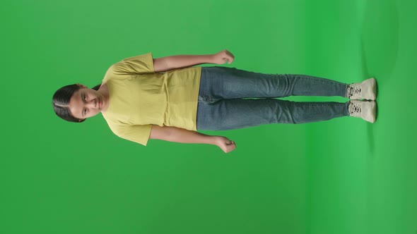 Full Body Of Terrible Asian Kid Girl Looking At Camera In The Green Screen Studio