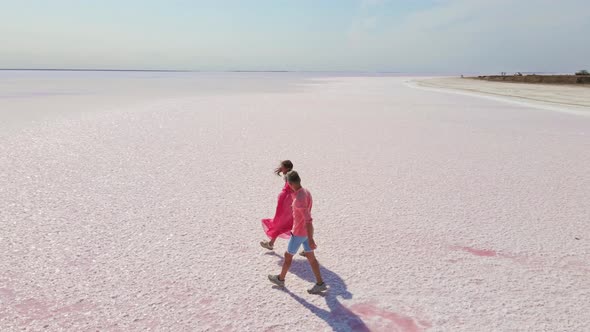 Aerial Drone Footage of Happy Young Couple in Pink Wear Having Fun and Joyfully Running