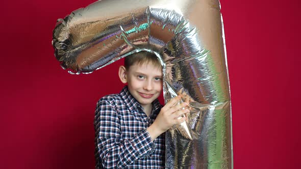 Birthday 7 years old child. Caucasian boy celebrating 7 years old holding an air balloon in the shap