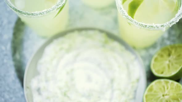 Key lime margarita garnished with fresh lime and salt in mason jar on metal tray.