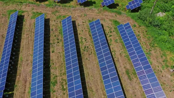 Solar panels among nature. Long rows of blue photovoltaic panels on the field. 