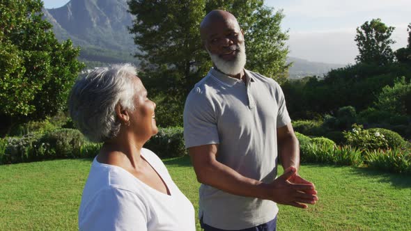 African american senior couple meditating together while standing in the garden