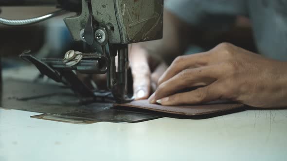 Close-Up Of Tailor Working On Sewing Machine in leather factory background