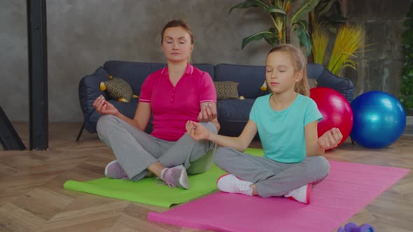 Relaxed Mom and Daughter Meditating in Lotus Pose