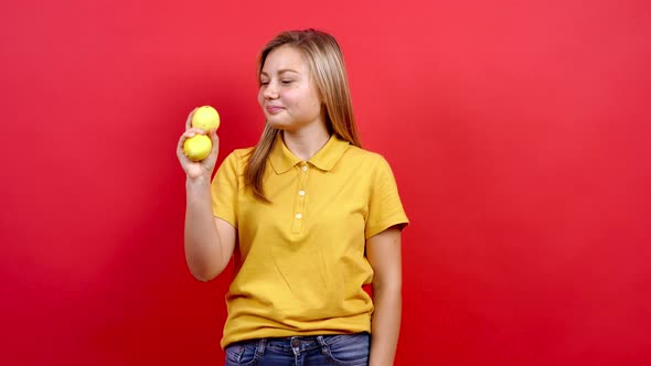 Cute and Slightly Fat Girl in a Yellow T-shirt Who Holds Two Fresh Lemons in Her Hand,