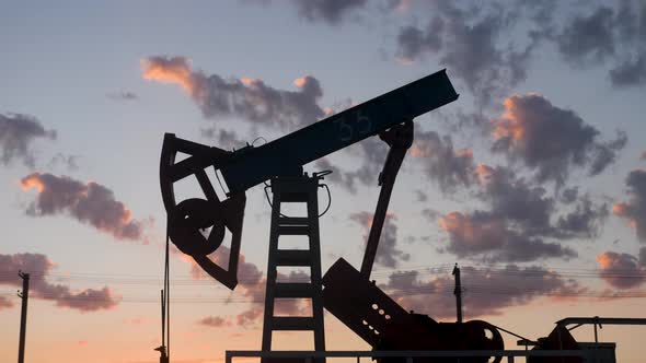 Oil Rig Stands in a Field at Sunset and Extracts Minerals