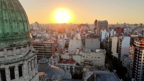 Aerial dolly out flying over Balvanera neighborhood revealing Argentine Congress building at sunset,