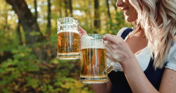 Happy Blonde Clicks Two Glasses of Beer at Her Lush Breasts at Autumn Forest