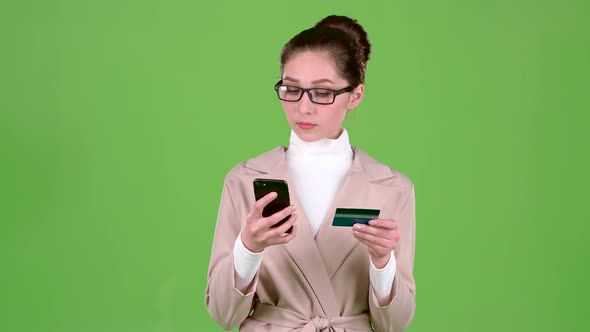 Bank Employee Holds a Phone and a Credit Card in His Hand. Green Screen