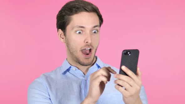 Wow, Surprised Young Man Using Smartphone on Pink Background