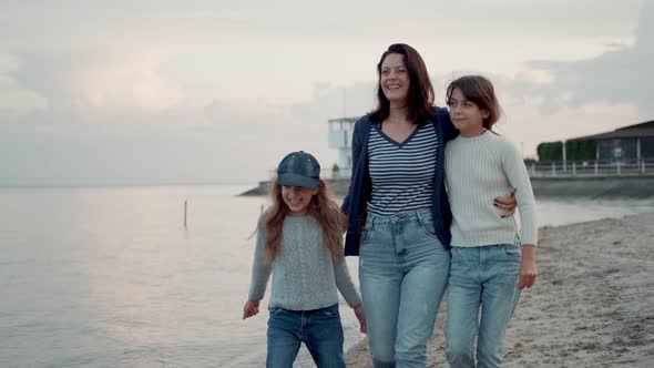 Family Walks Along the Seashore at Sunset. a Young Mother Is Having Fun with Her Children