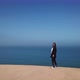 A Young Woman Walks Along Sandy Dunes on Seashore - VideoHive Item for Sale