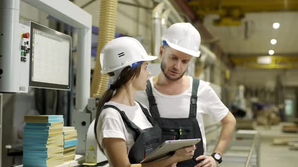 Portrait of Young Woman and Man Wearing Helmet and Overalls Working on Furniture Factory and