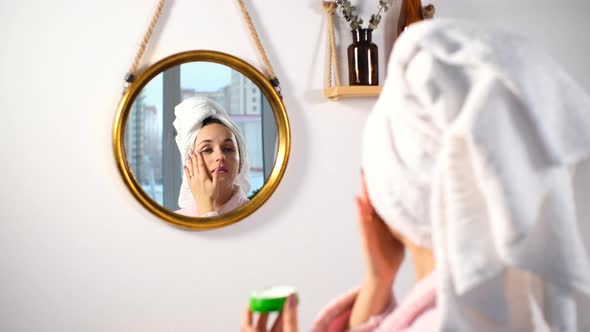 Female Applying Creme on Face After Taking Shower