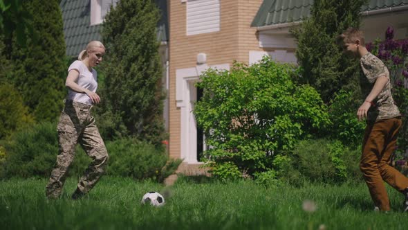 Wide Shot Female Recruit and Teenage Boy Playing Soccer in Slow Motion on Sunny Backyard Outdoors