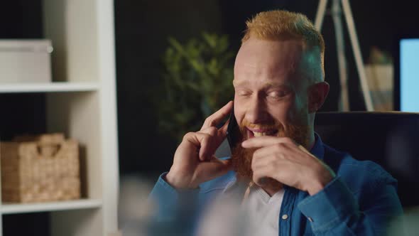 Smiling Hipster Man Talking on Mobile Phone at Home. Happy Guy Working at Home.