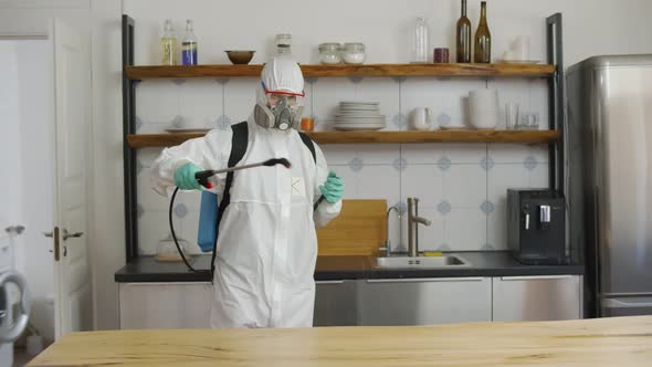 Disinfector in Protective Suit Spaying Kitchen with Chemicals