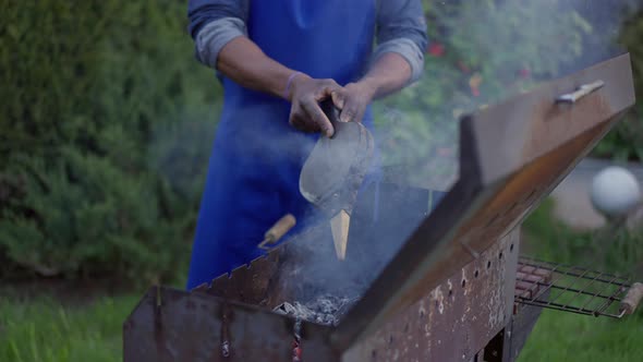 Unrecognizable African American Young Man in Apron Blowing Bbq Smoke Outdoors on Summer Day