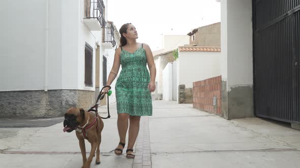 happy woman walking with boxer dog in the street