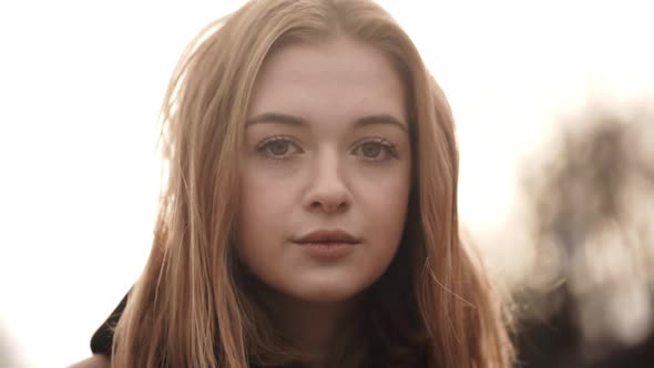 Closeup Portrait of Beautiful Female Having Natural Makeup Looking on Camera and Smiling While Wind