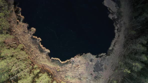 AERIAL TOP DOWN ESTABLISHING - Ice bather sits by a frozen lake