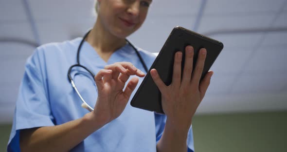 Midsection of portrait of caucasian female doctor using digital tablet in hospital room
