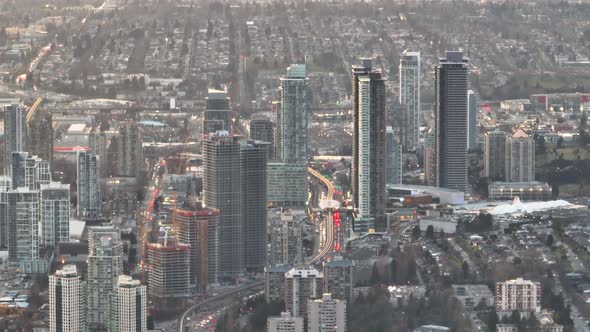 Aerial truck left of highway traffic, Sky Train and Brentwood Town Centre skyscrapers in Burnaby cit