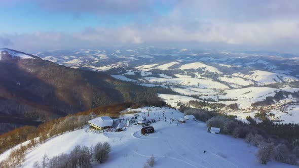 Old Ski Station on a Snowy Mountain Slope with a Lot of People on Skis and Snowboards