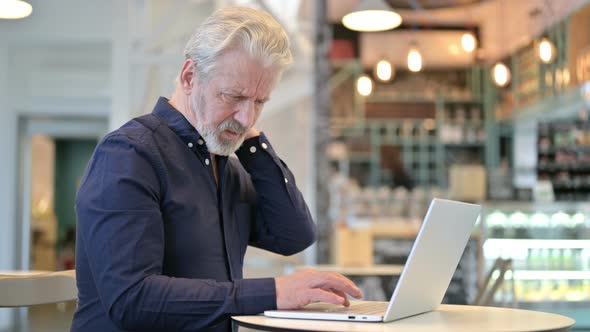 Laptop Use By Old Man with Neck Pain in Cafe