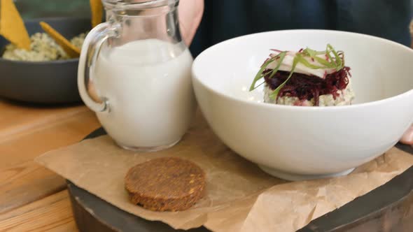 Person in Apron Puts Wooden Board with Vegetarian Dessert