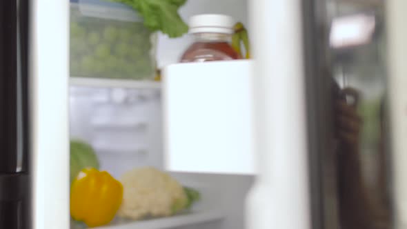 Hand Opening Fridge with Vegetables at Kitchen