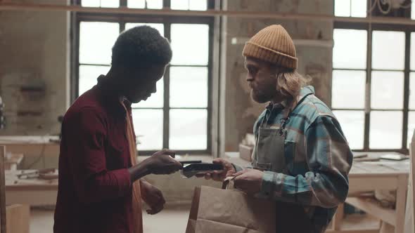 Male African Customer Paying Joiner Using Smartphone