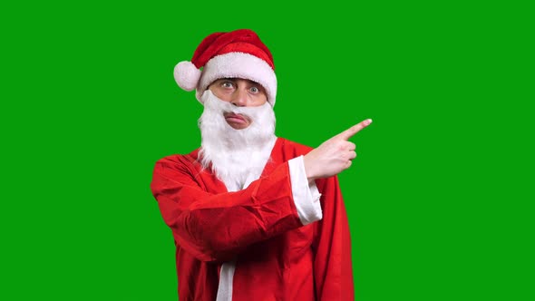 Santa Claus in Red Suit Pointing Aside on Green Chroma Key Background