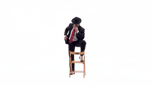 Elegant Man in a Black Hat Is Dancing an Erotic Dance, He Uses a Chair and a Cigarette