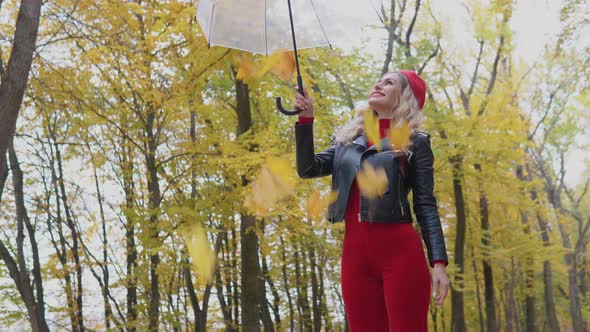 Smiling Happy Woman Raises an Umbrella with Leaves and They Fall Down