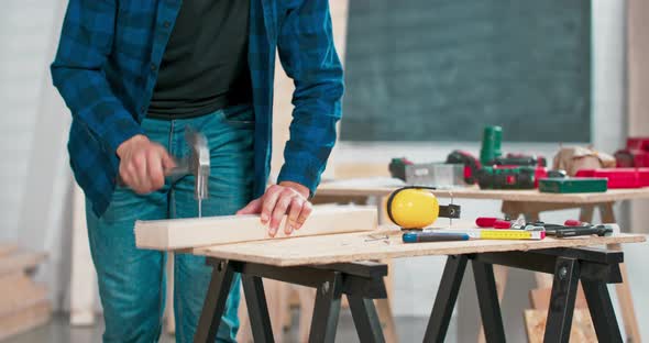 Close Up of Hammering a Nail Into Board A Carpenter Wearing a Red Flannel Shirt Jeans and Cloth