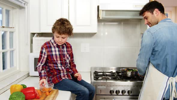 Boy helping father while cooking food in kitchen