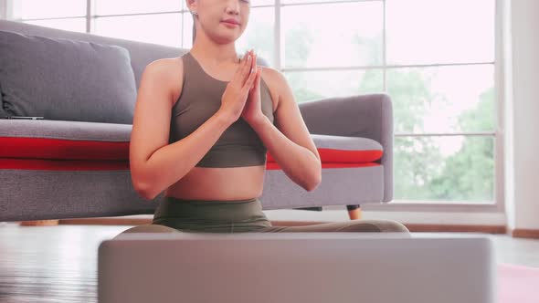 Asian girl is practicing online yoga from home.