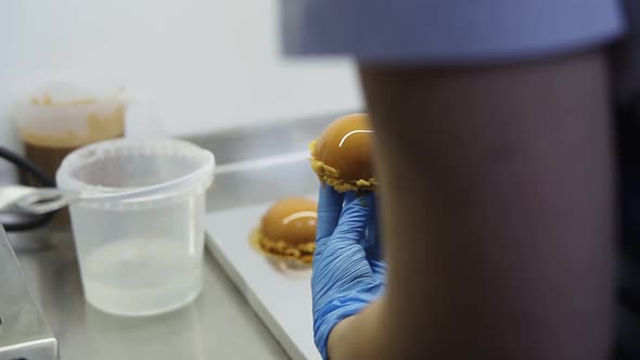 Confectioner in Blue Gloves Puts Caramel Glazed Cakes on Special Gold Carton Plates to Put It Out on