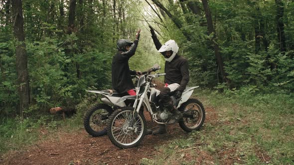 Motorcyclists High-Fiving and Riding Away in Forest