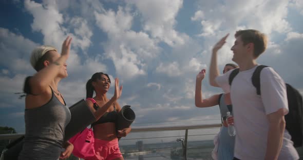 Young People Give High Five to Each Other Smiling Under Sky