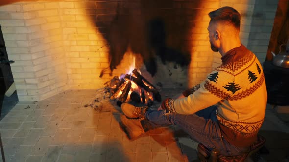 Man is sitting near the fireplace.