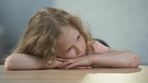 Depressed Curly-Haired Female Kid Sitting at the Table and Dreaming About Family