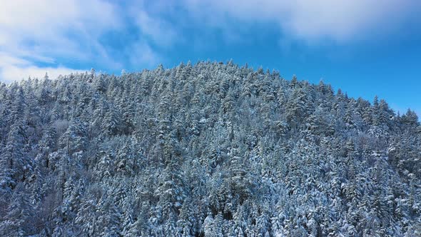 Aerial SLIDE to the right looking up at the peak of a snow covered mountain