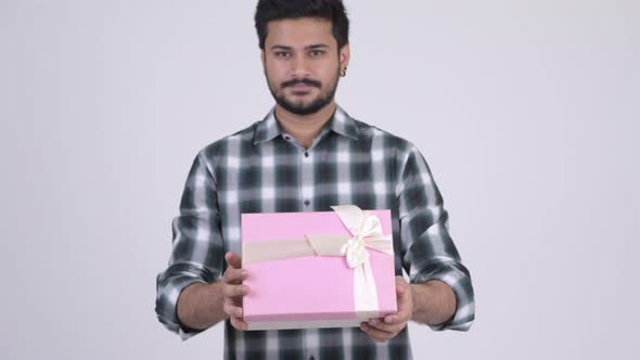 Portrait of Young Happy Bearded Indian Man Giving Gift Box